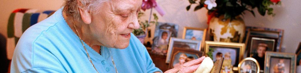 Elderly lady polishing picture frames showing family photographs